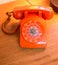 Retro orange rotary dial telephone.