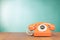 Retro orange telephone on wooden table in front gradient mint blue background. Vintage style photo