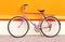 Retro pink bicycle stands over colorful orange