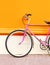 Retro pink bicycle stands over colorful orange background