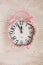 Retro pink clock on wooden background, top view