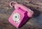 Retro pink rotary telephone on wood table