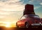 Retro red car with luggage on roof rack at sunset. Travel, vacation concepts.