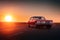 Retro red car standing on asphalt road at sunset