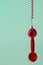 Retro Red Telephone Receiver Hanging by Spiral Cord on Aqua Back