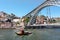 Retro riverboat sailing on the river Douro, under famous double-deck metal arch bridge