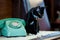 Retro rotary telephone on wood table and black cat sitting on wooden table