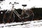 Retro rusty bicycle parking along street and bush under snow. Winter transport. Vintage bike.