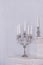 Retro silver candlesticks with white candles, isolated on white wall background. Vertical image.Intererniy light indoor
