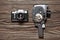 Retro SLR camera and mechanical movie camera on wooden background