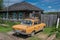 Retro Soviet Yellow Car Next to a Wooden House in the Siberian Outback