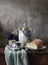 Retro still life poster breakfast. Vintage coffee pot kettle cups, silver spoon, homemade bread bakery. Dark light