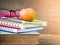 Retro style of apple on stacks of books with pink glasses and red pencil on wooden table background.