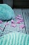 Retro-style photo of knitwork in progress and knitting accessories, amongst pink camellia blossom petals on wooden background