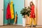 retro styled woman standing at ficus plant in flowerpot at colorful apartment doll