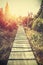 Retro stylized mountain wooden path in mountains at sunset.