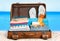 Retro suitcase with travel objects on beach