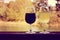 Retro sunset filter style image of two glasses of wine, white and red, on wooden rail