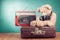 Retro Teddy Bear, old suit case and radio recorder in front mint blue background. Vintage style photo
