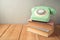 Retro telephone and old books on wooden table