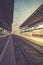 Retro toned perspective image of the sunlit railway platform wit