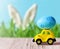 Retro toy car with Easter egg on the roof on spring background. Easter concept