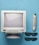 Retro tube TV, 3d glasses and remote control on a brown background. Top view, vintage video technology.