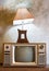 Retro tv with wooden case and lantern in room with vintage wallpaper