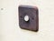 Retro vintage rusted Doorbell with patina on bronze and white button on a white wall