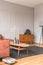 Retro wooden cabinet with black vases in the corner of classy grey living room interior with ginger sofa