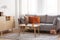 Retro wooden coffee table in front of grey couch in classy living room interior