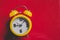 Retro yellow alarm clock with Nine Five Minutes Old Style, Top View on Red