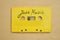 Retro yellow audio cassette tape with jazz music laying on the paper background.