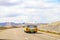 Retro yellow and white camper van drives away in badlands area of Utah near Arches National Park with start dessert background on