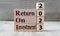 RETURN ON INVESTMENT 2023 - words on wooden blocks on gray background