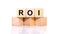 Return on investment, ROI. A cubic wooden block with an alphabet building the word ROI. Isolated