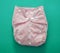 Reusable cloth baby diaper. Eco friendly nappy pink color on green background