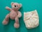 Reusable cloth baby diaper. Eco friendly nappy and teddy bear on green background