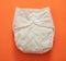Reusable cloth baby diaper. Eco friendly nappy yellow on orange color background