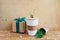 Reusable coffee mug with tube, green twig of Christmas tree, package with twigs, gift box with green ribbon on wooden background.