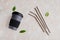 Reusable eco friendly sustainable handy bamboo cup and stainless steel metallic straws on beige background.