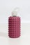 Reusable glass bottle for water in dusty pink rubber case with many spikes and plastic top comfortable for fingers. White backgrou