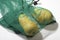 A reusable net bag for grocery shopping filled with fresh pears from the market, on a white background.