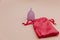 Reusable pastel purple menstrual cup and bag on a pink background. Alternative way of women's hygiene, menstruation