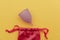 Reusable pastel purple menstrual cup and bag on a yellow background. Women's hygiene, menstruation, critical days