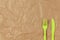 Reusable recyclable green fork, knife made from corn starch on brown crumpled craft paper, copy space. Eco, zero waste,