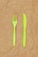 Reusable recyclable green fork, knife made from corn starch on brown crumpled craft paper, copy space. Eco, zero waste,