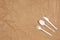 Reusable recyclable white fork, spoon, knife made from corn starch on brown crumpled craft paper, copy space. Eco, zero waste,
