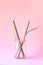 Reusable stainless steel straws and cleaning brush in glass bottle on pink background, eco friendly lifestyle