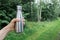 Reusable stainless thermos bottle for water in female hand to replenish the body`s water reserves against the forest